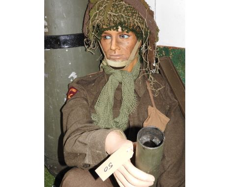 A seated mannequin in South Stafford badged khaki with camouflage helmet and shoulder magazine holder 