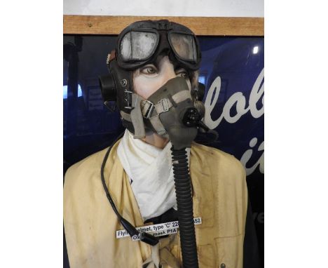 A standing mannequin wearing blue uniform, preserver jacket, holding peaked cap, wearing leather gloves and suede flying boot