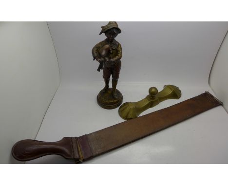 A French spelter figure of a boy playing pipes, a leather strop marked Langbourn and a brass door stop