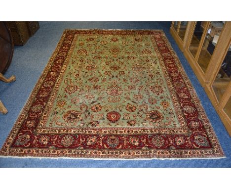 A Tabriz carpet, the turquoise central ground with allover red and gold foliate decoration surmounted by red foliate border, 