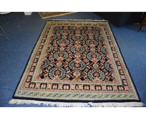 A Persian Hamadan carpet, decorated with multiple floral motfis on blue ground, geometric border, 340cm x 244cm