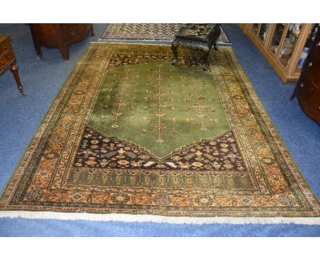A Persian carpet, decorated with three long floral motifs on green ground, with gold floral border, 350 x 252cm CONDITION REP