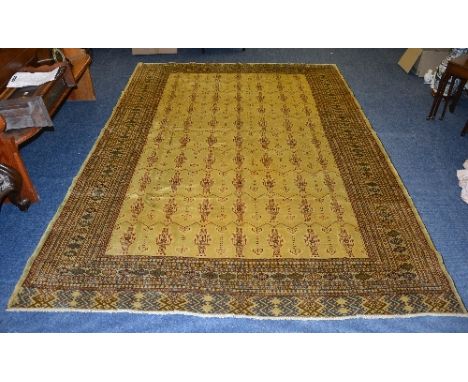 A Turkman carpet, the yellow ground with allover brown geometric patterns, with multiple brown and blue patterned border, 292