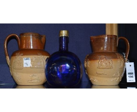 Two Doulton Lambeth relief moulded pottery jugs, 18 & 19cm high, also with vintage blue glass flagon, 19cm high (3)