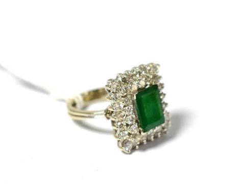 An emerald and diamond cluster ring, the oblong step cut emerald within a double border of round brilliant diamonds in white 