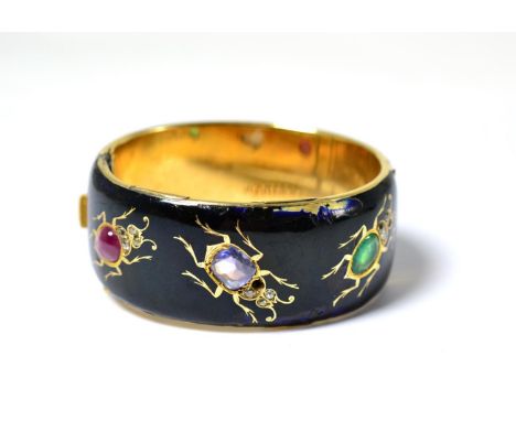 A 19th century Russian insect bangle in 56 standard gold, enamelled and set with a pear cut emerald, a cushion cut sapphire a