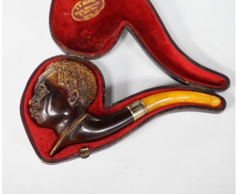 A cased Meerschaum pipe with a bowl modelled as a Nubian man’s head with metal mount and amber mouthpiece, 14cm long The neck