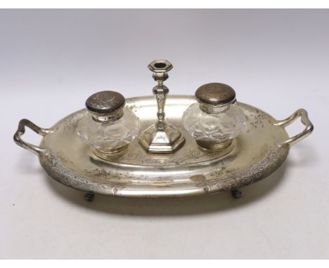 A Victorian engraved silver oval two handled inkstand, with two mounted glass wells and a taperstick, on four scroll feet, He