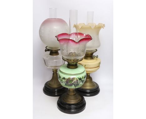 Three glass and brass oil lamps, c.1900, tallest 57cm Shade with red rim in good condition; base of shade 10cm wide; green oi