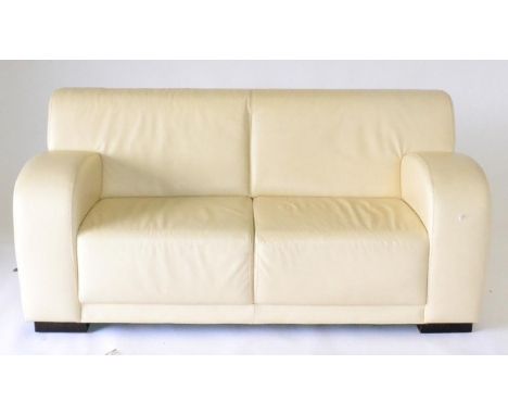 A Pair of Cream Leather Sofas, of recent date, comprising a three-seater sofa with rounded arms and stained black block feet,