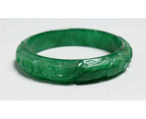 A CHINESE CARVED APPLE GREEN JADE BANGLE.