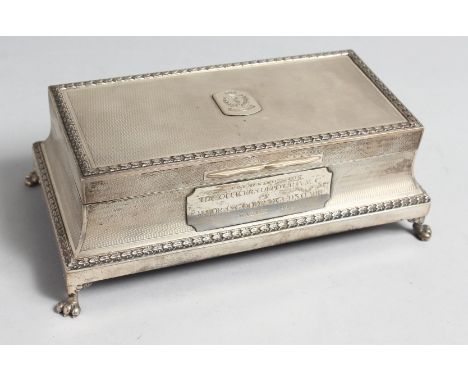 AN ENGINE TURNED SILVER RECTANGULAR CIGARETTE BOX on four claw feet, 8ins long, cedarwood liner, London 1936, with inscriptio