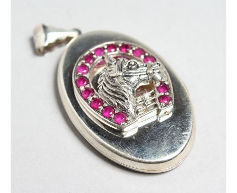 A SILVER AND RUBY OVAL LOCKET with horse head and horse shoe decoration, 1.5ins high.