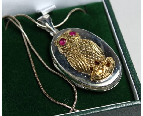 A SILVER OWL LOCKET with ruby eyes and chain.