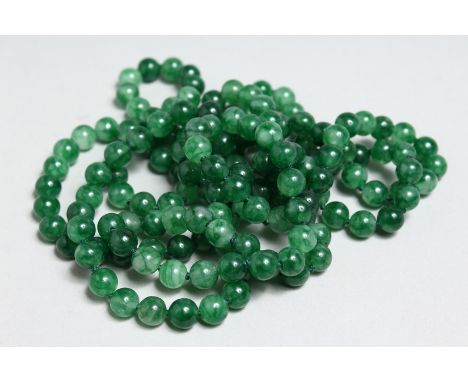 A LONG STRING OF DARK GREEN JADE BEADS, 50ins long.