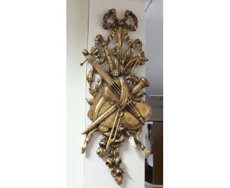 A carved giltwood wall bracket, decorated musical instruments with ribbon tie surmount, 110cm high Condition Report: Some spl