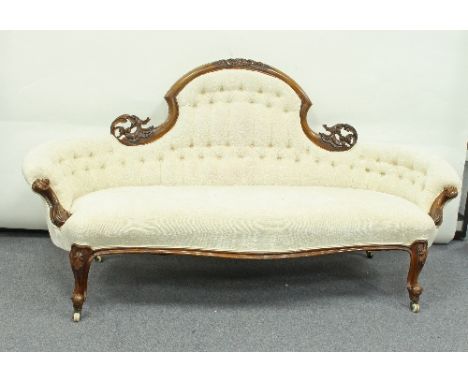 A Victorian carved walnut framed sofa, the arch crest rail carved scrolls above a button back and serpentine seat on carved l