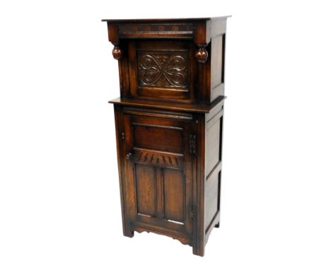 An oak court or press cupboard, with a rectangular top, above a carved panelled door enclosing a single shelf, above a cupboa