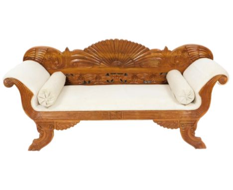 A Regency style hardwood sofa, with a carved floral back, scrolling arms, raised on outswept feet, with scatter cushions and 