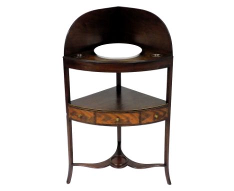 A George III mahogany bow front corner washstand, the galleried top with a recess for a bowl, and two smaller recesses, above
