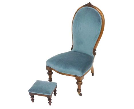 A Victorian mahogany spoon back nursing chair, upholstered in light blue draylon, raised on turned legs, brass capped on cast