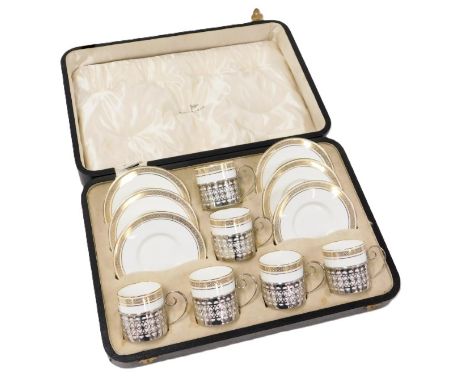 A George V Wedgwood porcelain and silver mounted coffee set, decorated with a gilt band of stylised flowers, in pierced silve