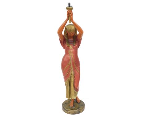 A 20thC painted novelty standard lamp, modelled as a Pharoahess, in standing pose holding aloft a light holder, raised on a c