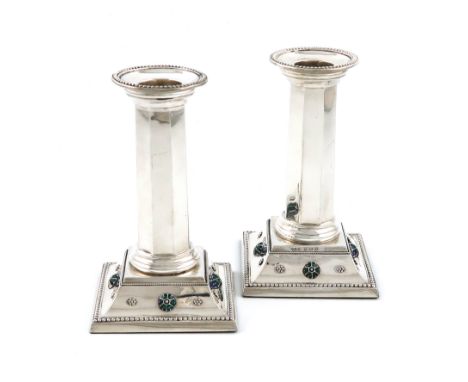 By Liberty and Co, a pair of Edwardian silver and enamel candlesticks, Birmingham 1907, faceted columns, beaded and rope-work