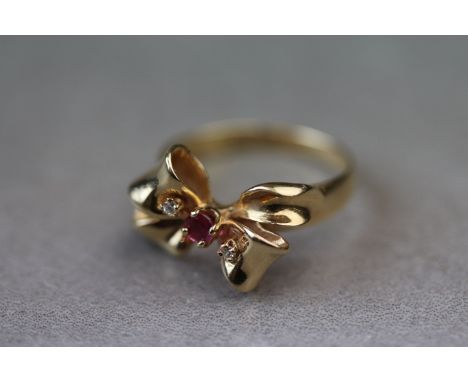Stuart Devlin: The jewelled bow ring; ruby and diamond 14ct yellow gold ring modelled as a ribbon bow, round mixed cut ruby f