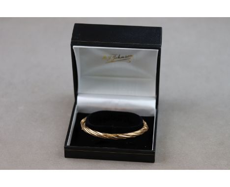 A 9ct yellow gold hinged bangle of writhen form to both halves, pin and box clasp with safety catch 