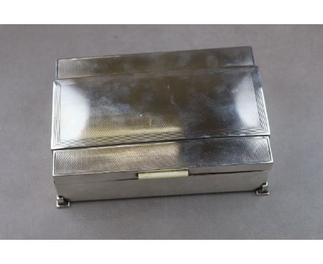 Art Deco silver cigarette box with ivory clasp, raised on four stepped feet, engine turned decoration to stepped lid, makers 