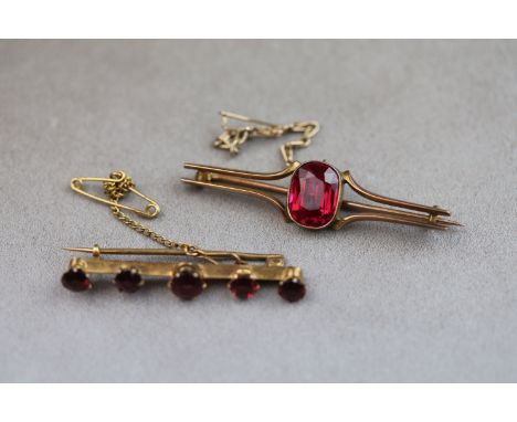 An Edwardian garnet 9ct yellow gold bar brooch, five round graduated mixed cut garnets set to knife edge bar, the centre larg