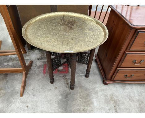 A VINTAGE MIDDLE EASTERN BRASS CIRCULAR TOPPED COFFEE TABLE WITH CARVED FOLDING DESIGN BASE, 27.5" DIAMETER 