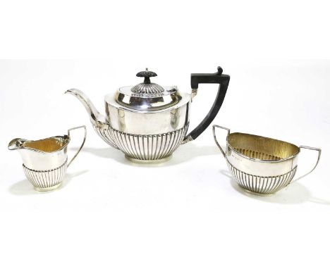 An Edwardian hallmarked silver harlequin three piece tea service, with demi-fluted detailing, Birmingham 1904 and 1919, maker