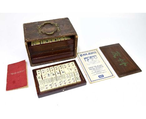 A Chinese Mahjong set, with simulated ivory counters in a stained wood box.