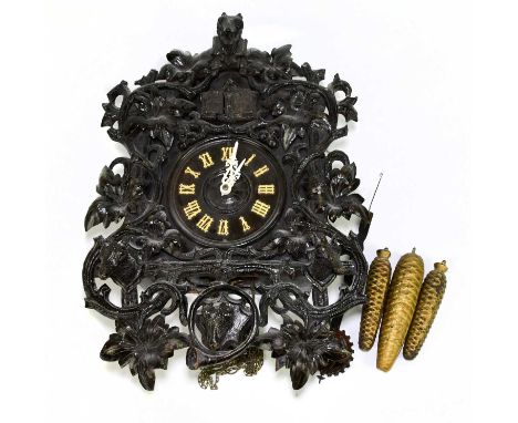 A late 19th century Black Forest cuckoo clock, ornately carved with stags' heads and floral detail, complete with weights, le