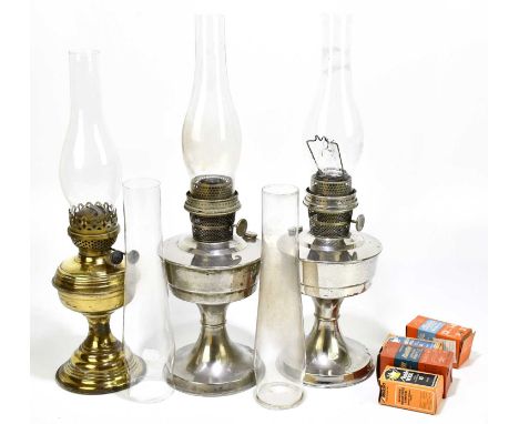 Two chrome oil lamps, height 30cm, with a brass oil lamp, five glass chimneys, etc.