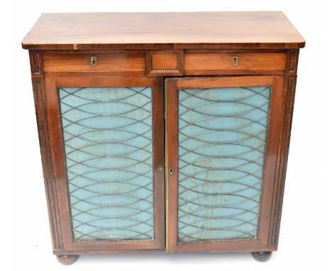 A Regency rosewood cabinet with two drawers above two metal and tapestry panelled doors enclosing a thick shelf with two base