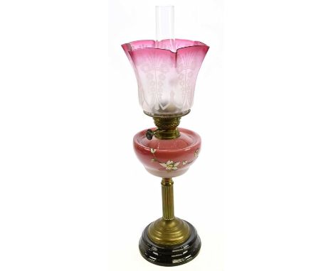 A late Victorian brass oil lamp with cranberry and clear frosted glass shade, etched decorated with floral detail above the m