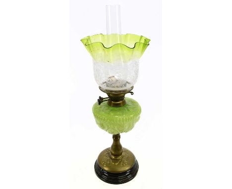 An Art Nouveau oil lamp with green and clear glass shade etched with floral detail above the moulded green glass reservoir, t