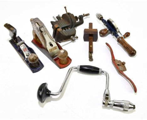 A small collection of woodwork tools to include two cast iron planes, a drill and a vice.