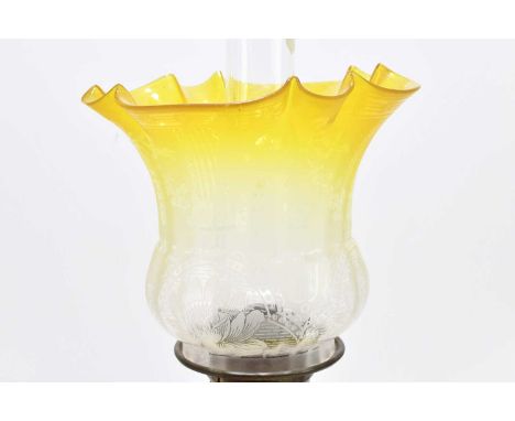An early 20th century oil lamp with yellow and clear frosted glass shade above the moulded yellow glass reservoir, height inc