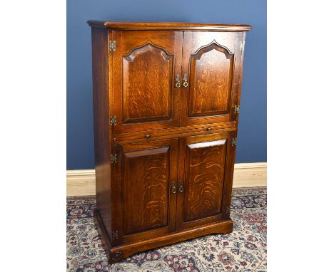 THE ROYAL OAK FURNITURE COMPANY; a reproduction oak cocktail cabinet with two panelled doors with single shaped shelf above s