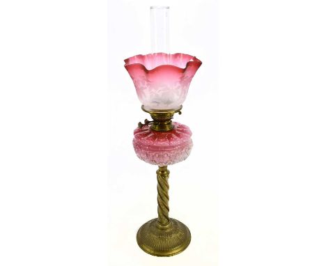A late Victorian brass oil lamp, the cranberry and clear glass shade with etched floral decoration above the moulded glass re