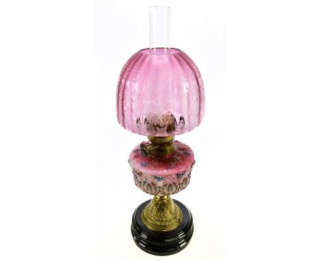 A late 19th/early 20th century oil lamp, with dome shaped cranberry coloured shade, with etched floral decoration above the m