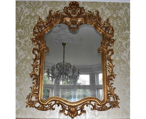 A large reproduction Chippendale style mirror, the frame decorated with scrolling laurel leaves and shell shaped rim, 190 x 1