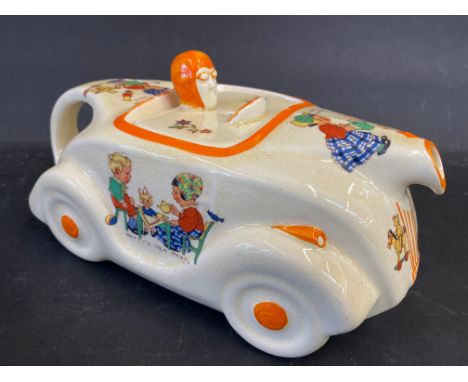 An Art Deco ceramic teapot in the form of a streamlined racing car decorated with nursery scenes. 