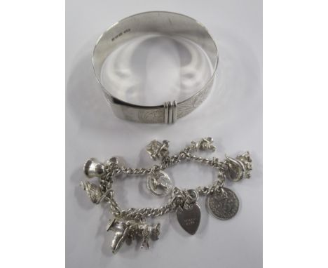 A silver bangle, together with a silver charm bracelet
