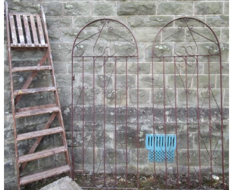 A pair of metal curved top gates, each 73ins x 29ins, together with a wooden step ladder (step ladder for decorative purposes
