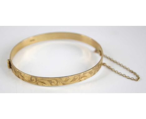 A Victorian style 9ct gold hinged bangle, having bright cut leaf trailing decoration, centre hinge with safety chain, 11.9g, 
